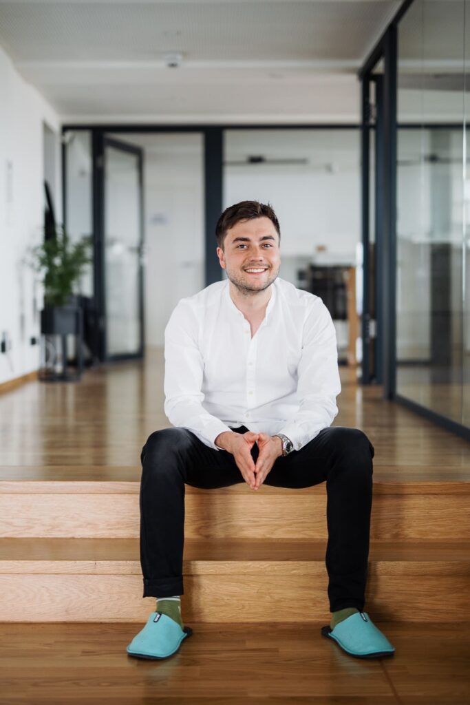 Lächelnder Mann sitzt auf Treppe im Büro.
