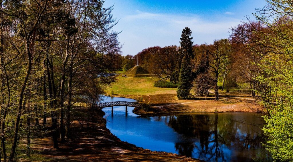 Landschaft mit Brücke, Fluss und Pyramide im Park